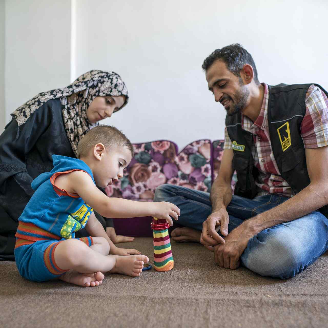 Anas, an IRC Reach Up & Learn volunteer and Syrian refugee, reads and plays with Rashid, 2 years old, at Rashids parent's home.