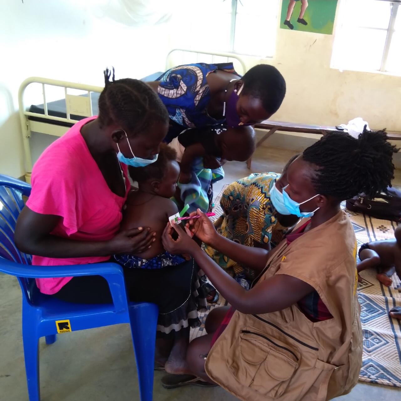 Esther, an IRC nutrition assistant, uses the mid-upper arm circumference measure (MUAC) to quickly identify if the child is at risk of malnutrition. When measured properly against a bare upper arm, the paper gauge provides a number and indicates the colour range. The green colour here is positive - the child is not showing signs of malnutrition.