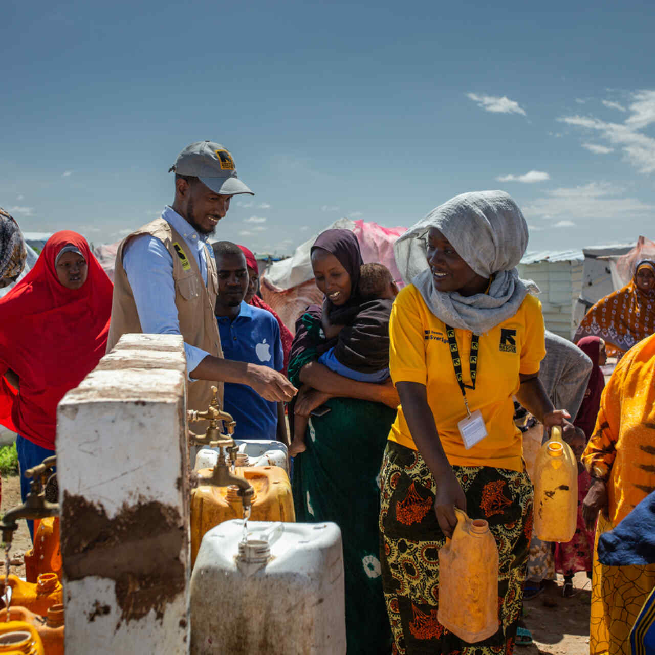 RESCUE event: Två av RESCUE:s medarbetare står vid en vattenbrun och fyller på vattendunkar.