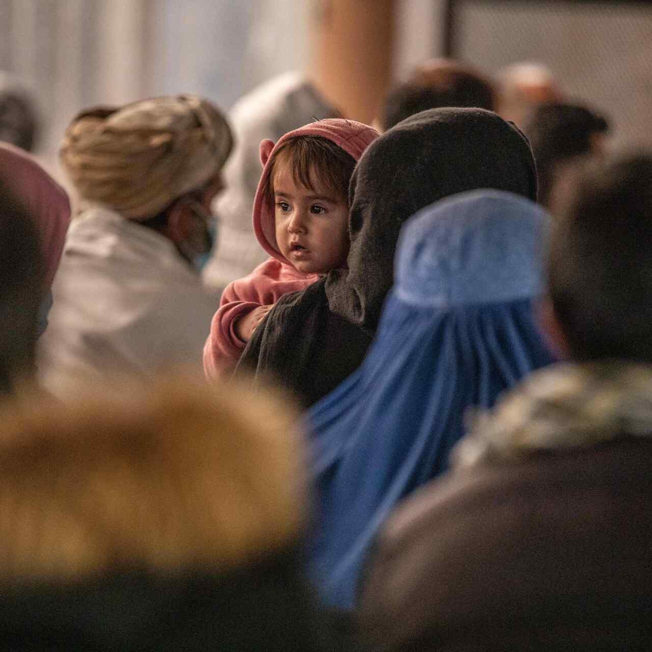 A woman carrying her child through a crowd.
