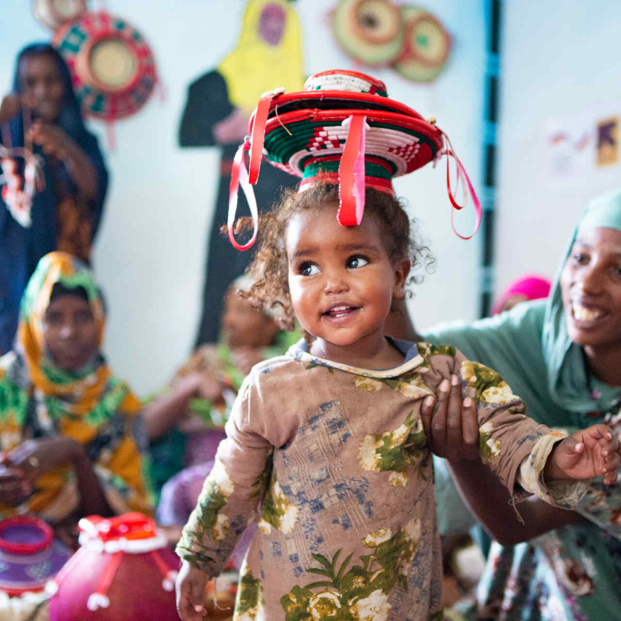 Ein kleines Mädchchen lacht während sie typisch äthiopische Handwerkskunst präsentiert
