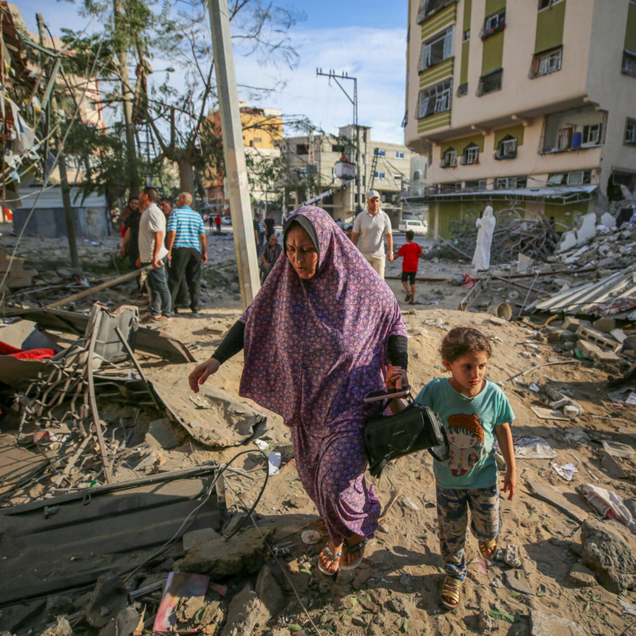 A woman and child pick their way through the rubble after an airstrike hits Gaza City.