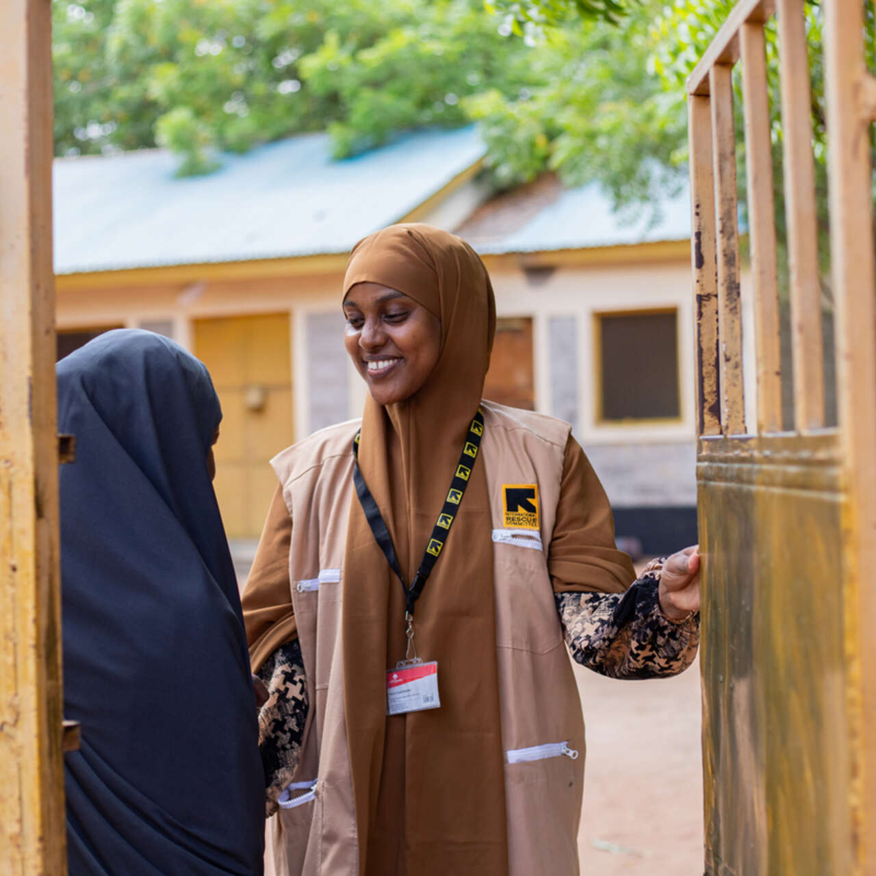 Två kvinnor i Kenya står och pratar vid en öppen grind