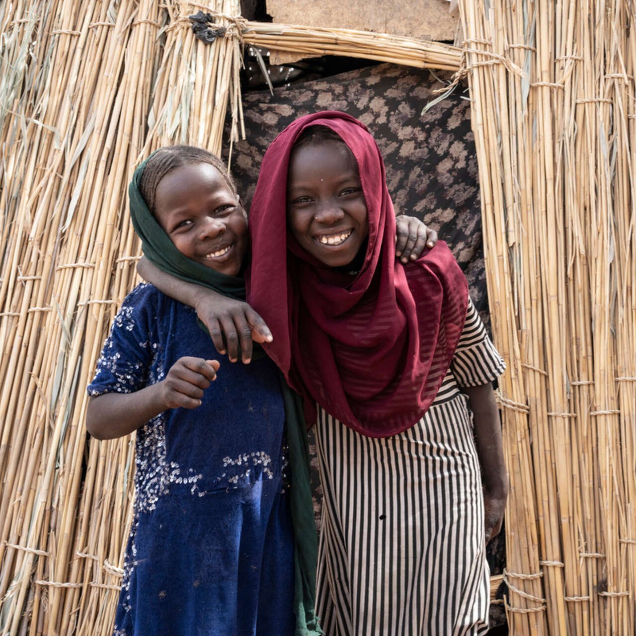 Två flickor i Chad håller om varandra och ler.