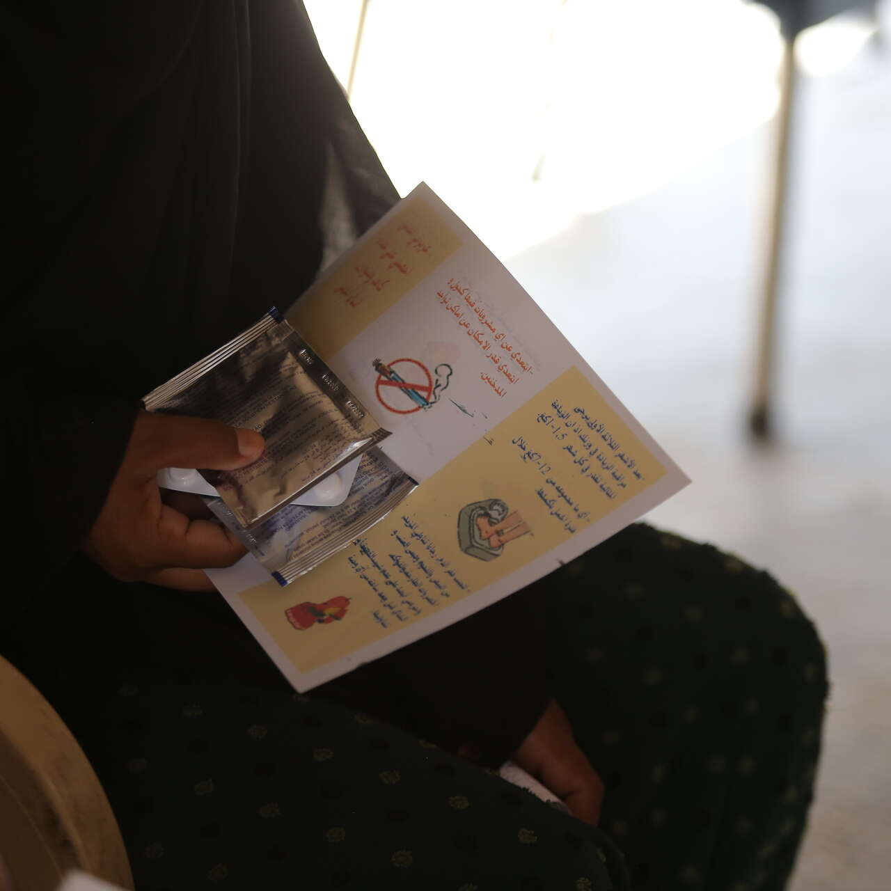 A person holds a health pamphlet in their hands at an IRC health centre in Syria.