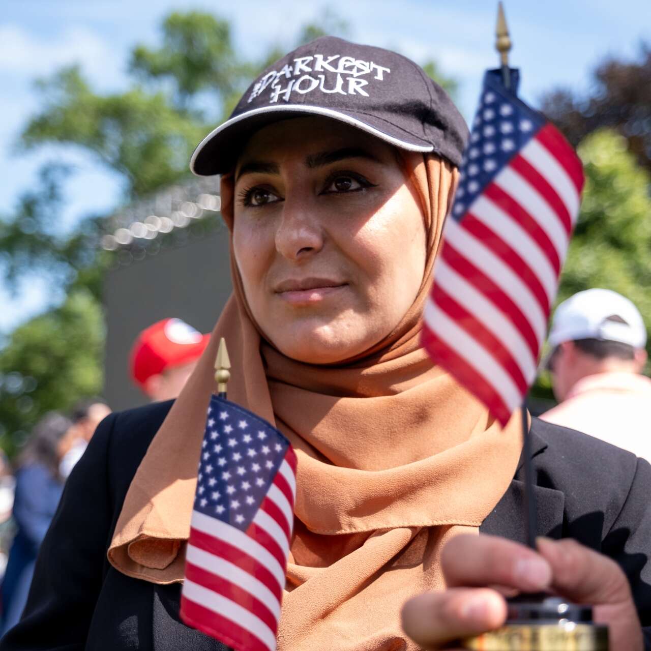 A newly naturalized American citizen has her portrait taken. U.S. flags are featured in the background.