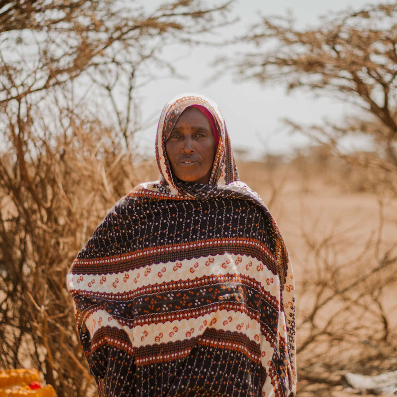 한 여성이 임시 거처 앞에서 앉아 있습니다.