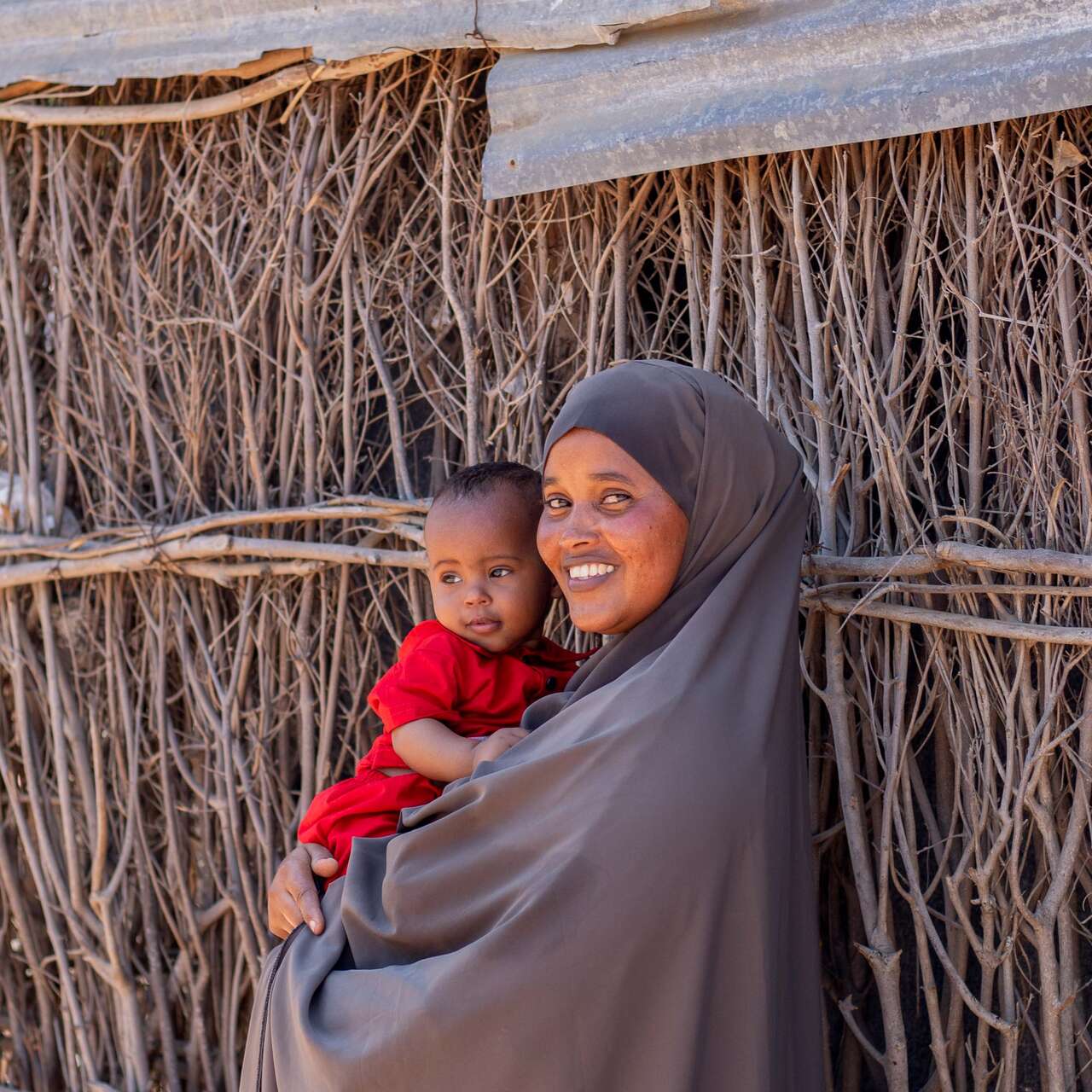 한 여성이 아기를 안고 환하게 웃고 있습니다.