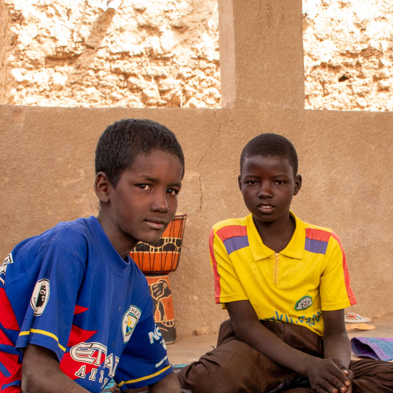 부르키나파소 소년들이 앉아서 카메라를 바라보고 있습니다.