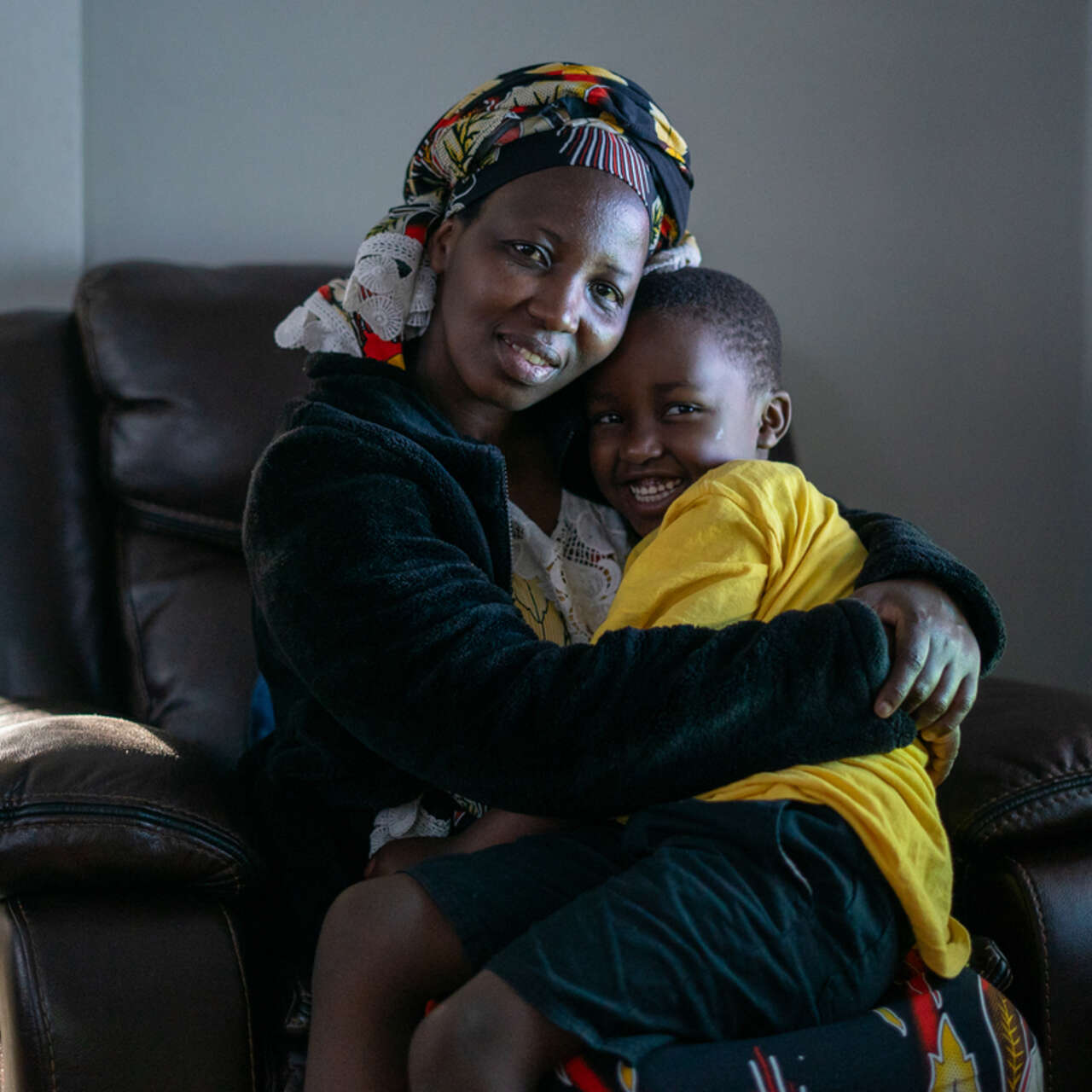 Bonfils mother, Nyabeza Nyabigazi, sits with her son, hugging him.