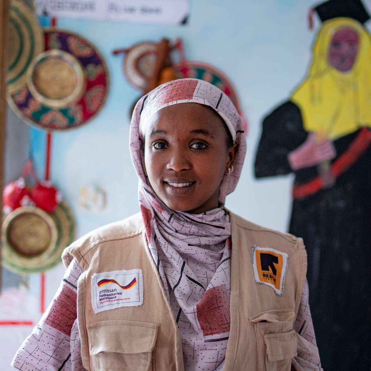 Eine lächelnde Frau in traditioneller Kleidung steht in einem dekorierten Raum.