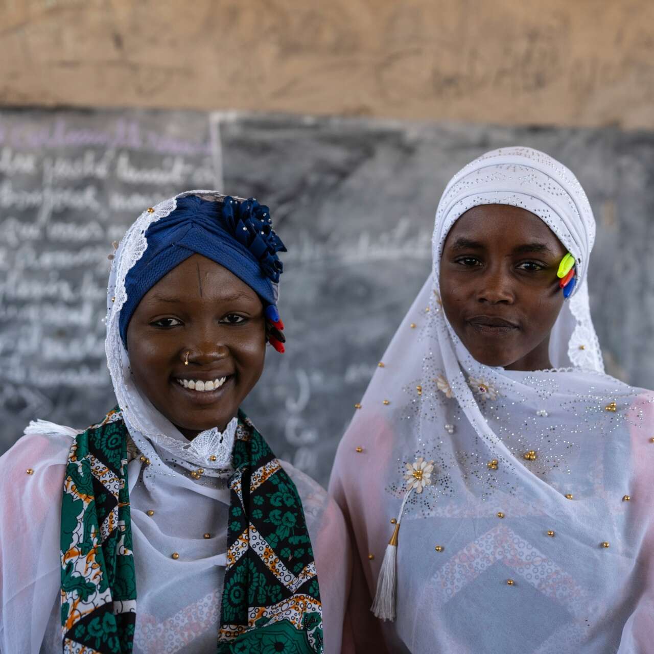 Two students stand at the front of a school in Chad and pose for a photo.