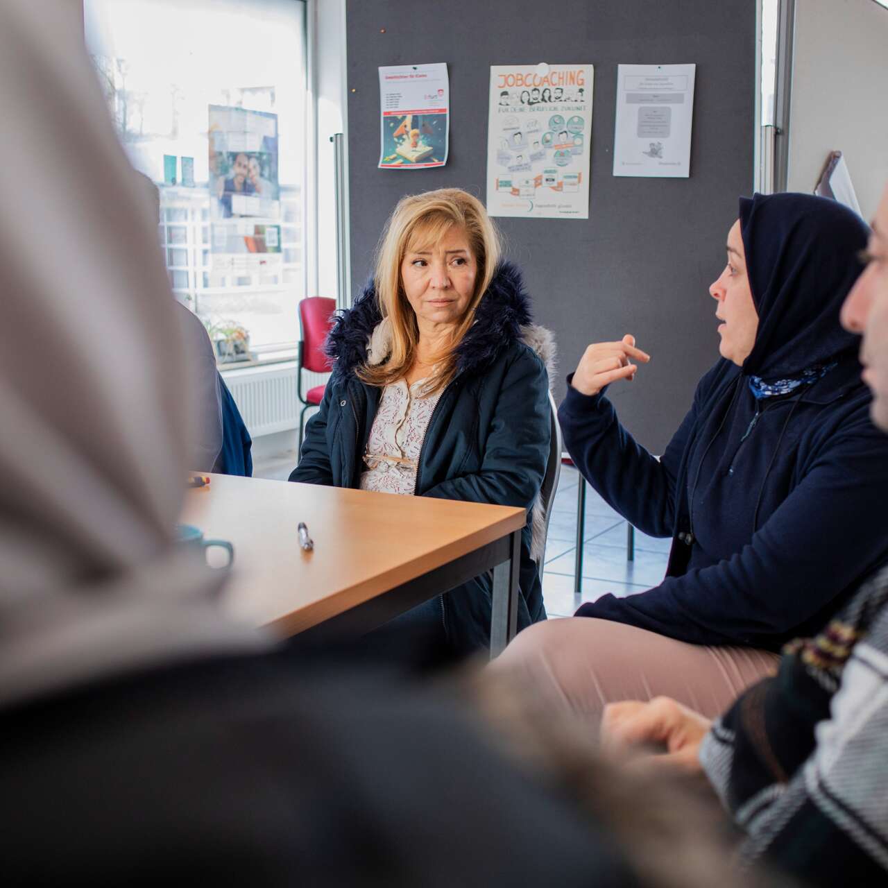 Menschen in einem Gespräch in einer Gemeinschaftseinrichtung, die in einem Raum zusammen diskutieren.