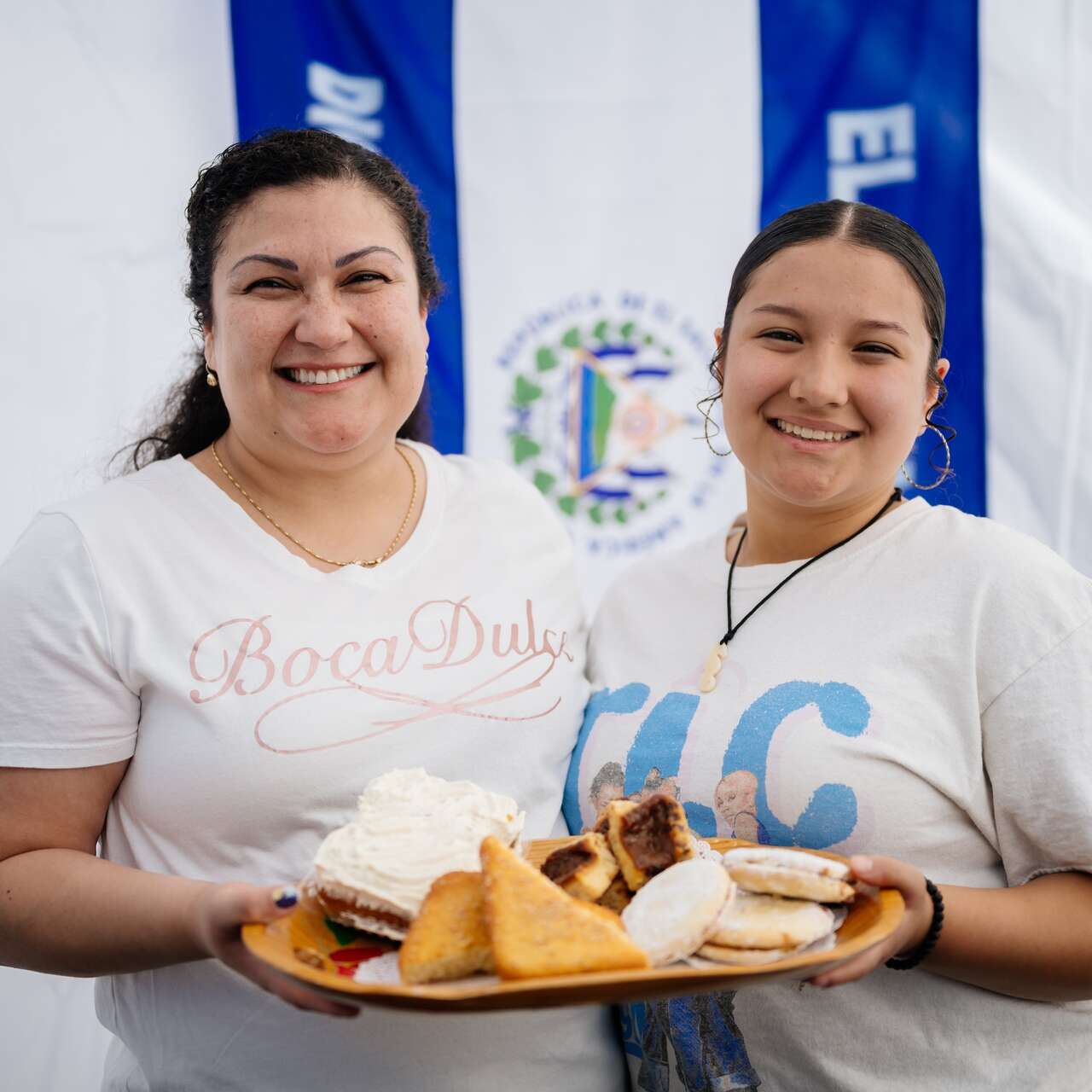 Two women smiling at the camera and holding a plate of food