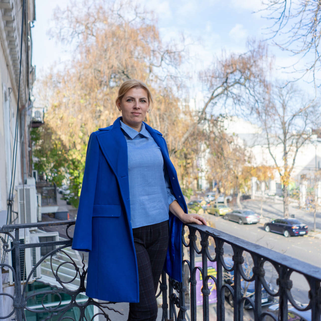Kvinna i Ukraina står på en balkong och tittar mot kameran.