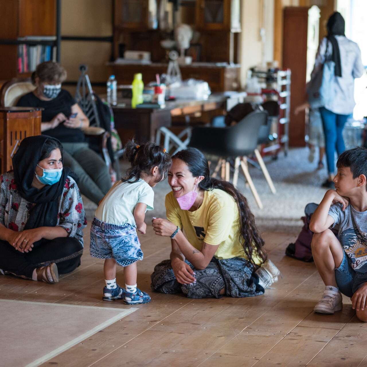 Erwachsene und Kinder spielen drinnen zusammen.
