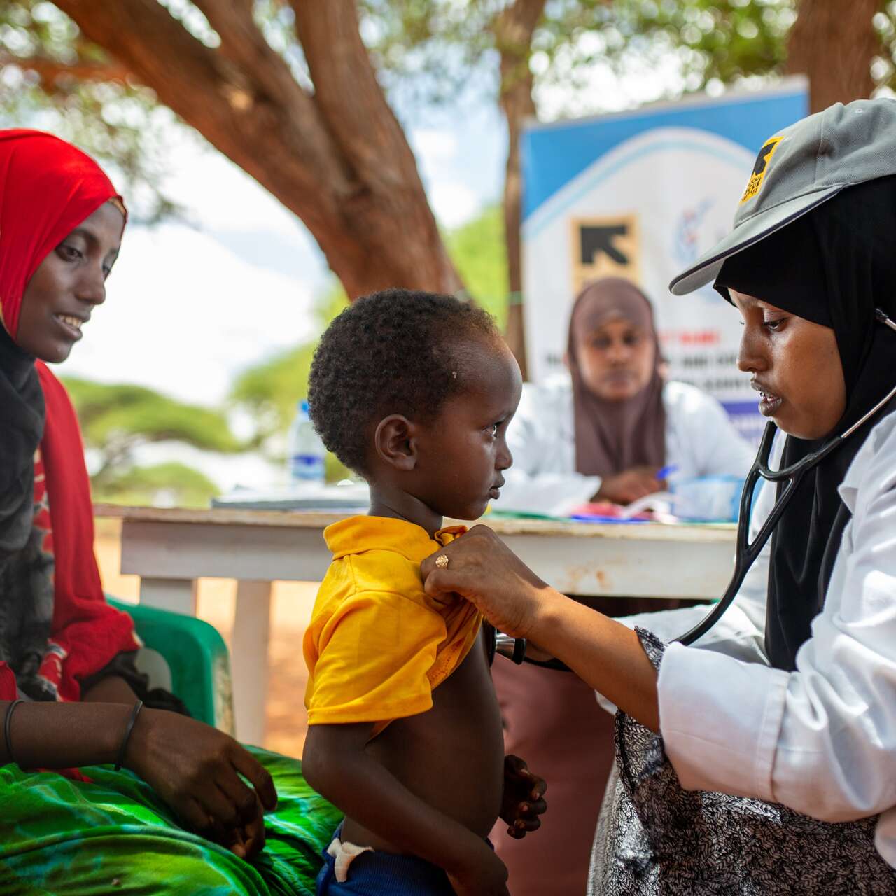 Ärztin untersucht Kind mit Stethoskop.