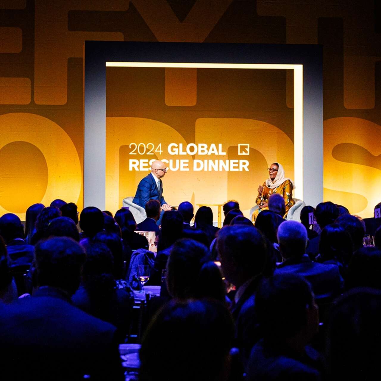 Two speakers share a conversation on the stage of the IRC's 2024 Global Rescue Dinner.