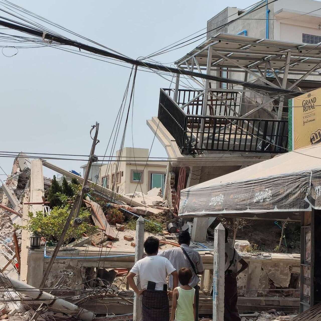 미얀마 지진 현장에서 사람들이 무너져내린 잔해를 바라보고 있습니다