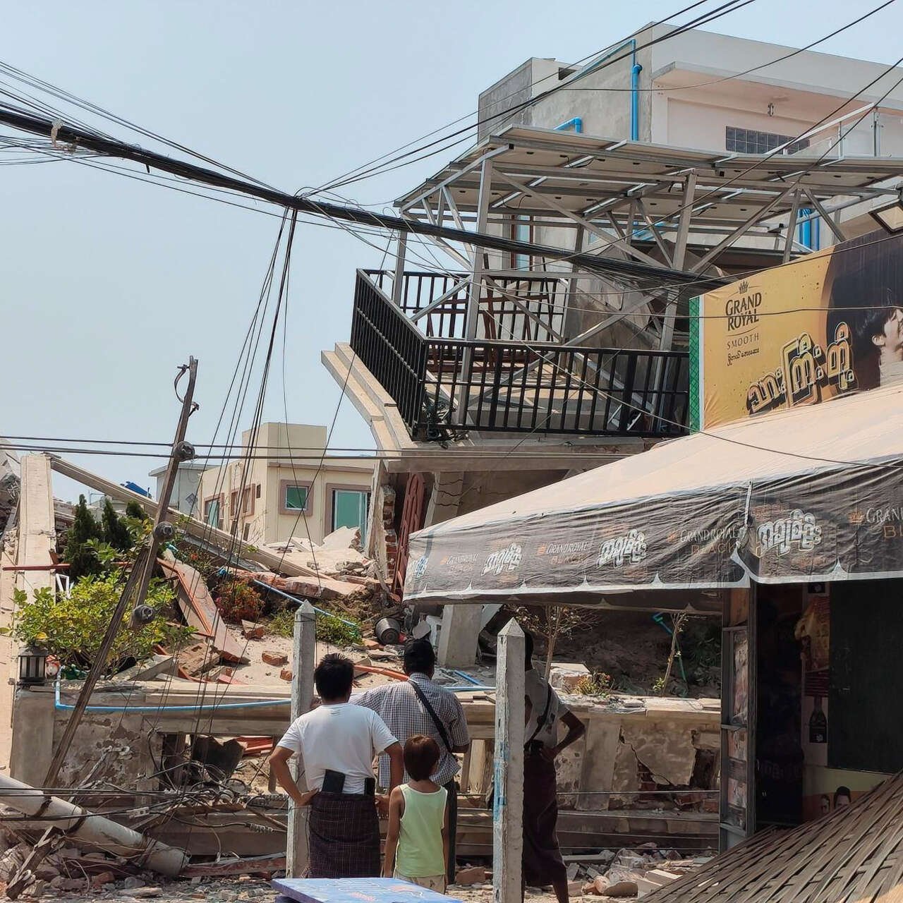 A family examines the severe destruction of their neighborhood, destroyed by the earthquake in Myanmar.