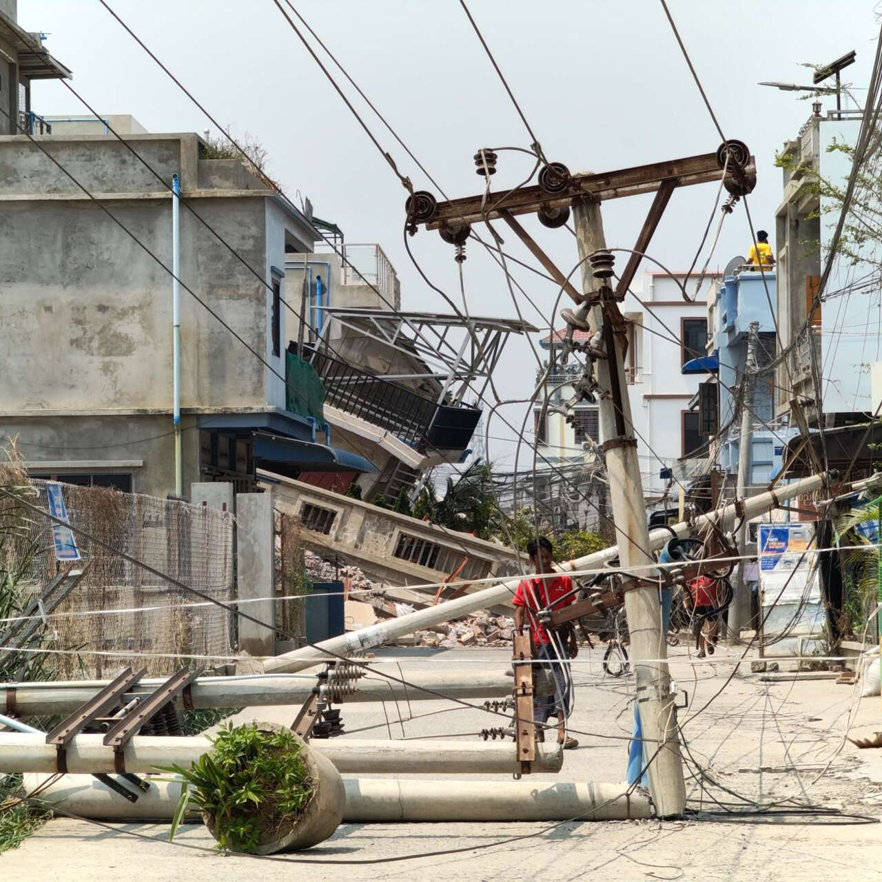 En man undersöker en nedfallen kraftledning som orsakats av jordbävningen i Myanmar.