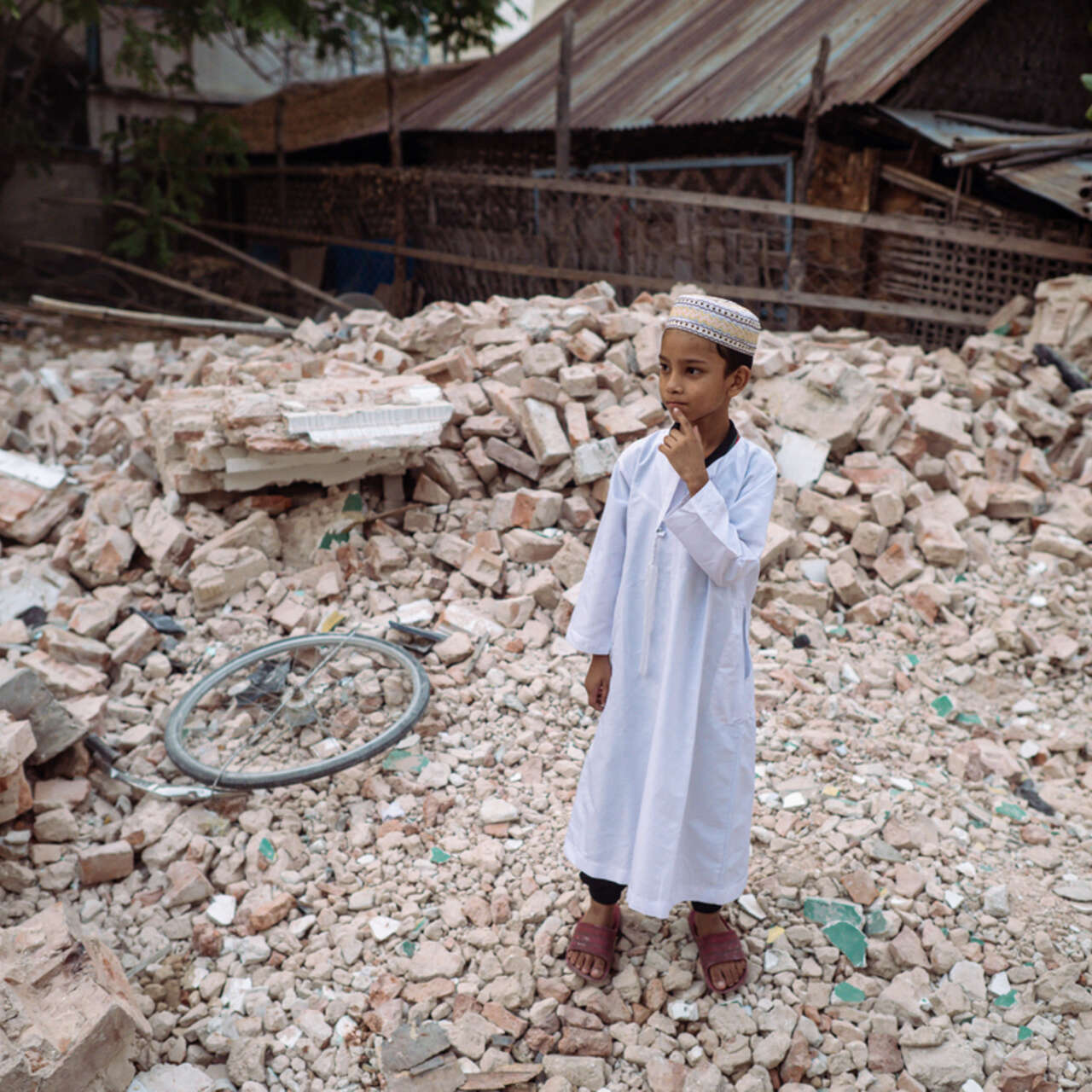 En liten pojke står mitt i rasmassorna efter jordbävningen i Myanmar 2025.
