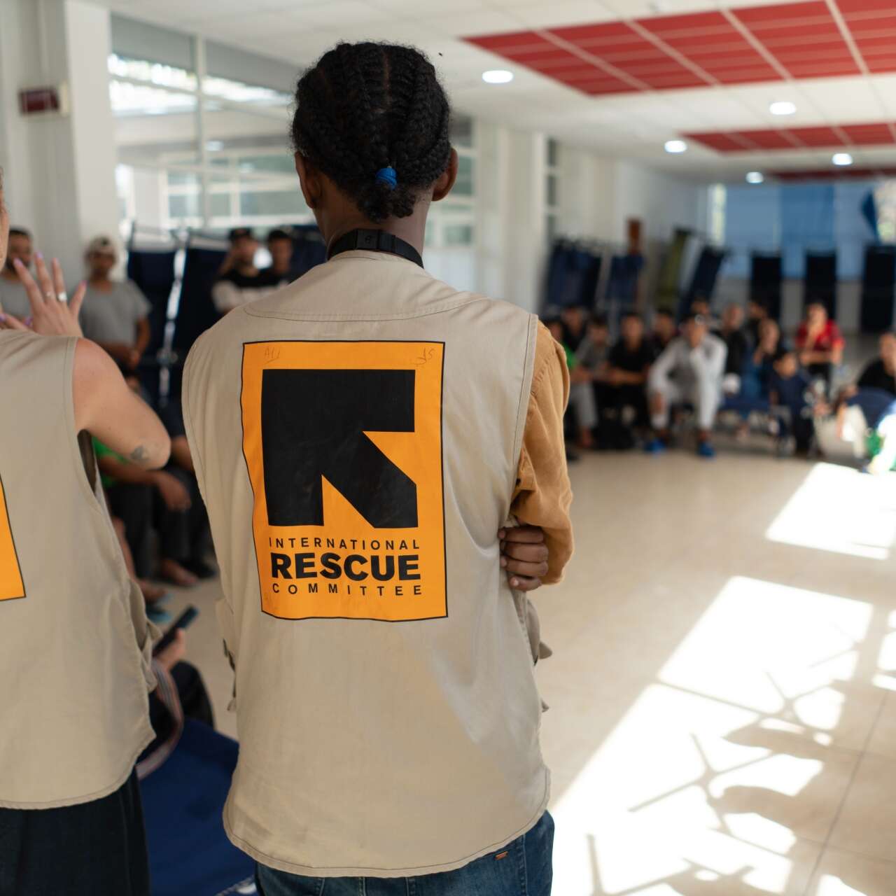 Two IRC staff members address a group of asylum seekers in Italy.