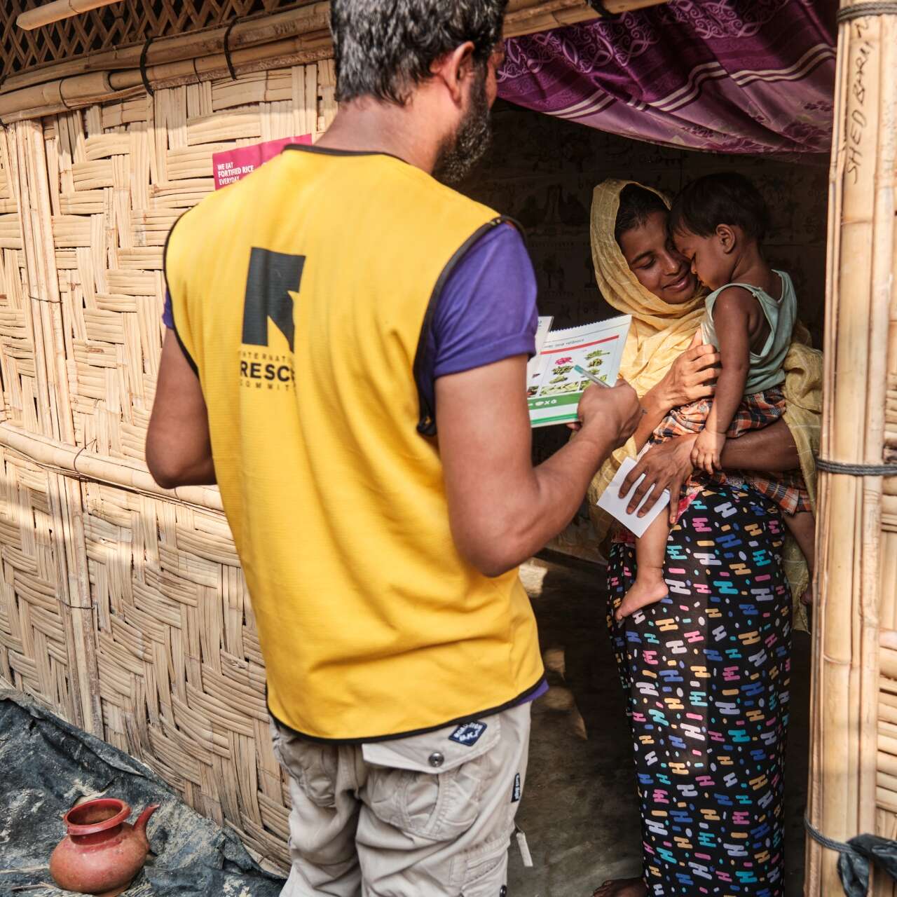 An IRC caseworker checks on a mother and her daughter at their home in a refugee camp in Bangladesh.
