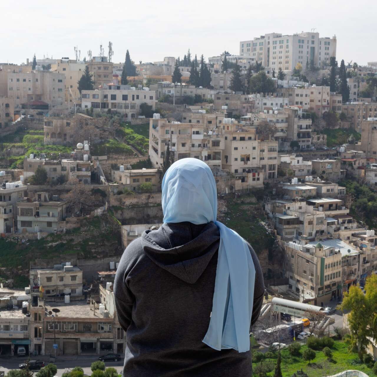 A Syrian refugee stands atop a hill in Amman, Jordan where she looks out at her new home.
