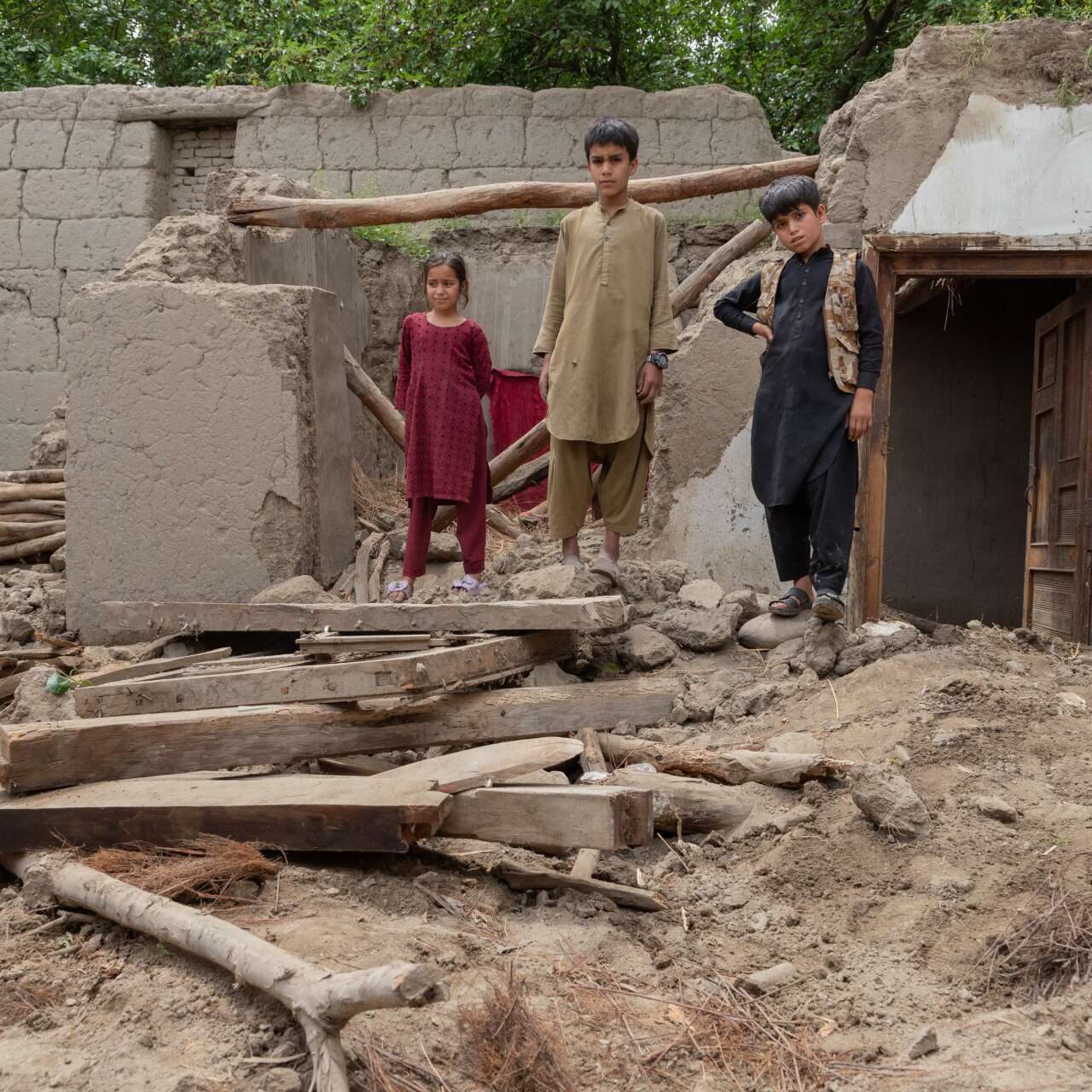 Three children walk through the ruins of their home-devastated by severe flooding.