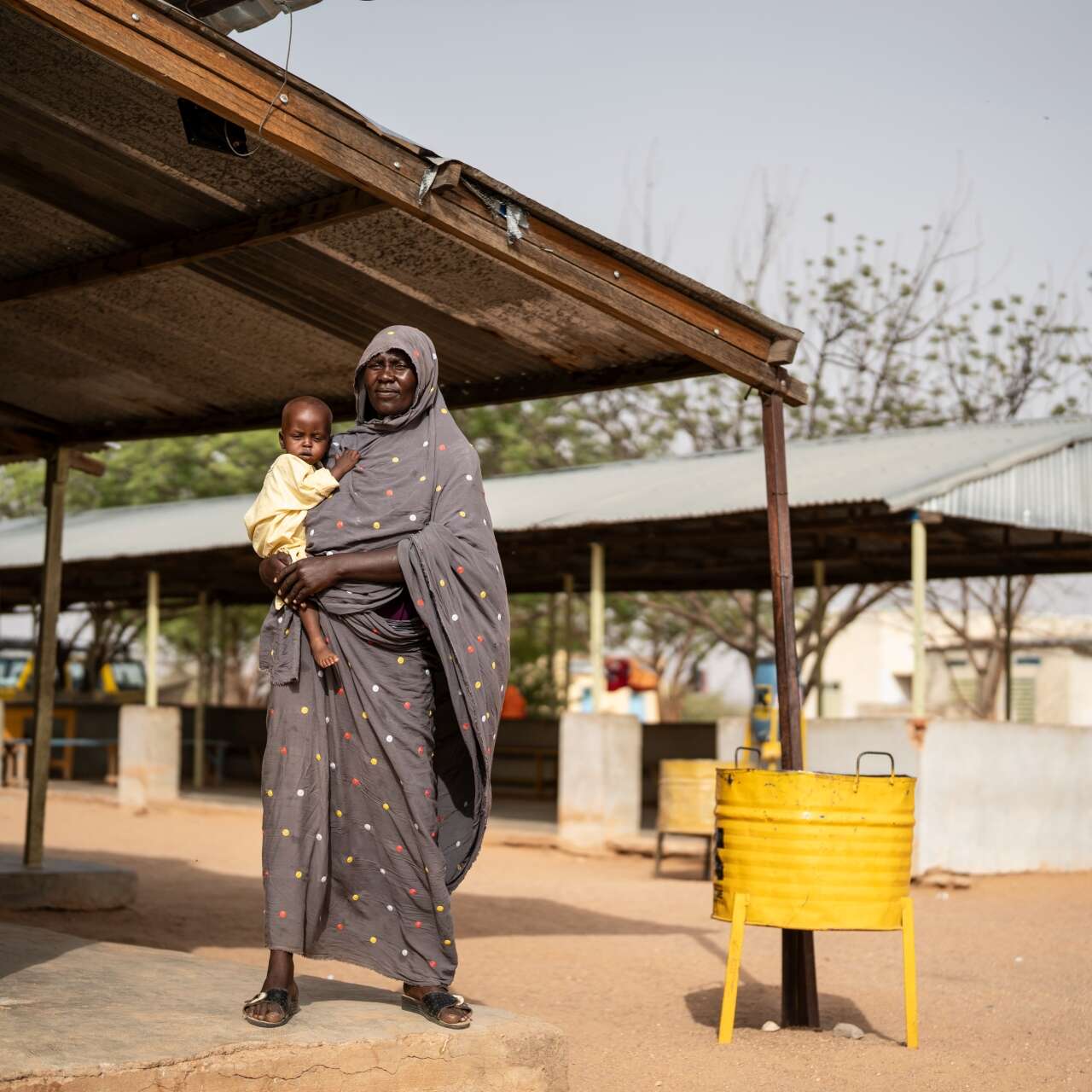 Khamissa, 70, holds her young grandson, Djaba, in her arms.