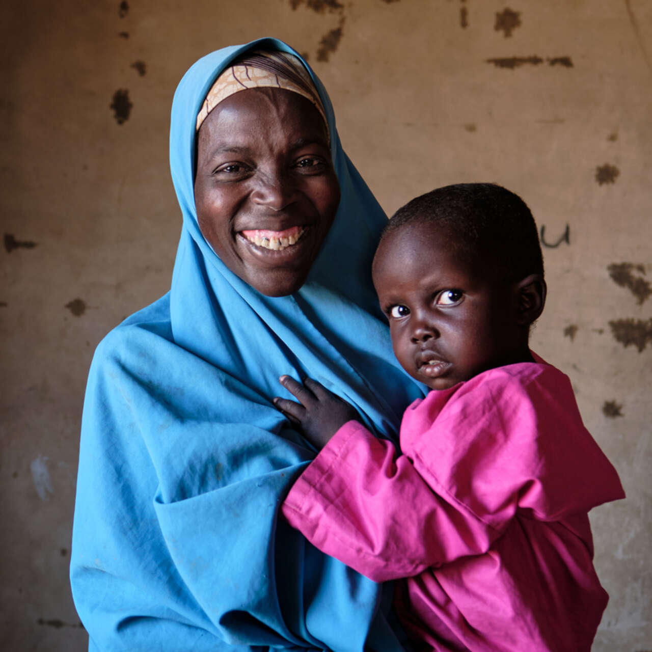 En mamma står och håller i sitt lilla barn.