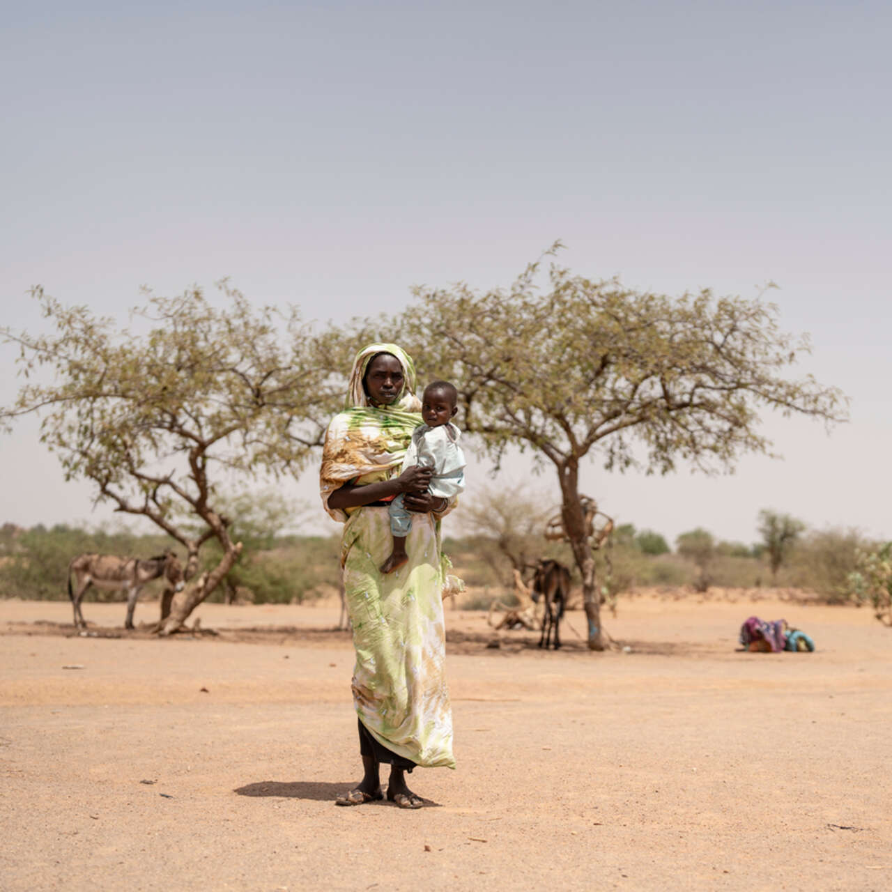 En kvinna står och håller sitt barn i famnen i Tchad