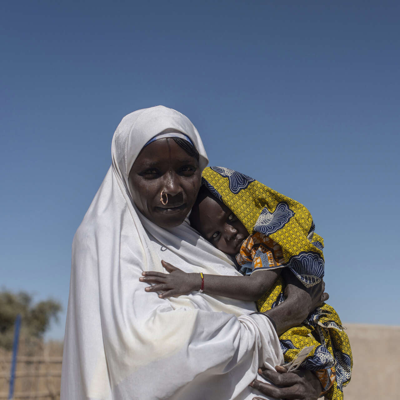 차드의 한 고객이 자녀를 품에 안고 카메라를 바라보고 있습니다