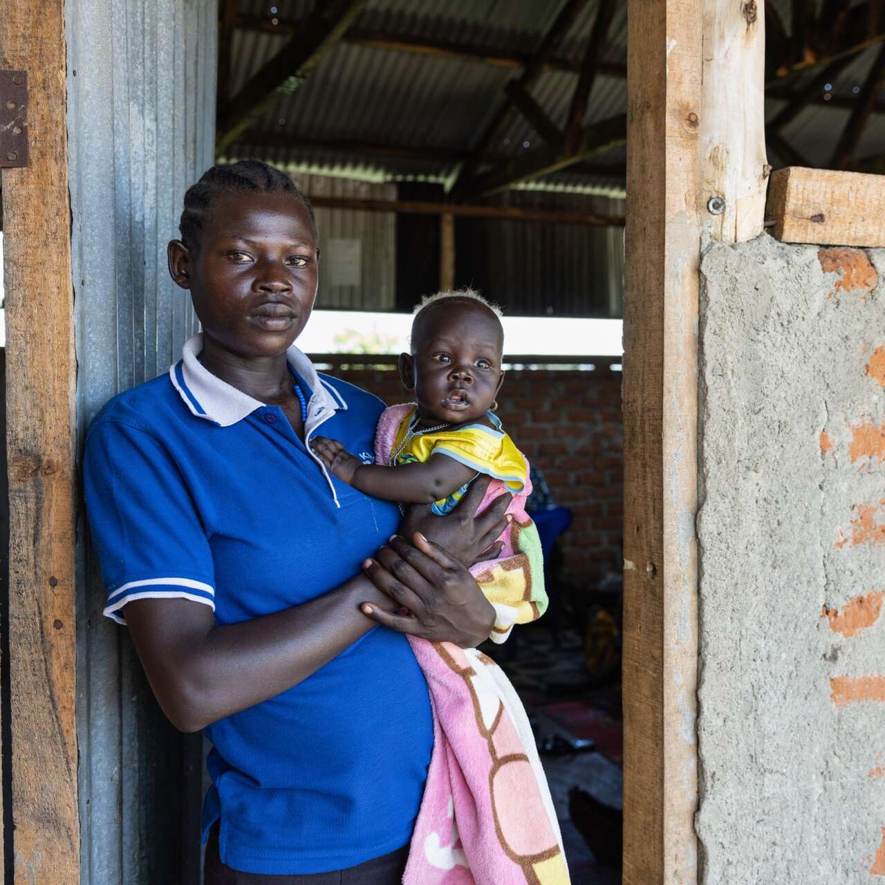 A young woman holds her baby in her arms and poses for a photo.