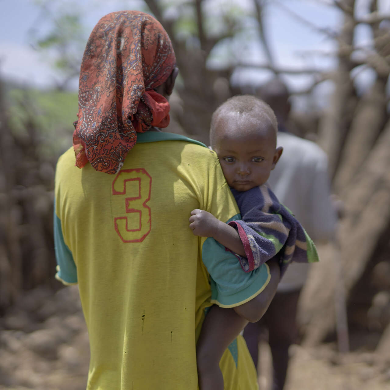 한 에티오피아 어린이가 엄마의 품에 안겨 카메라를 응시하고 있습니다.
