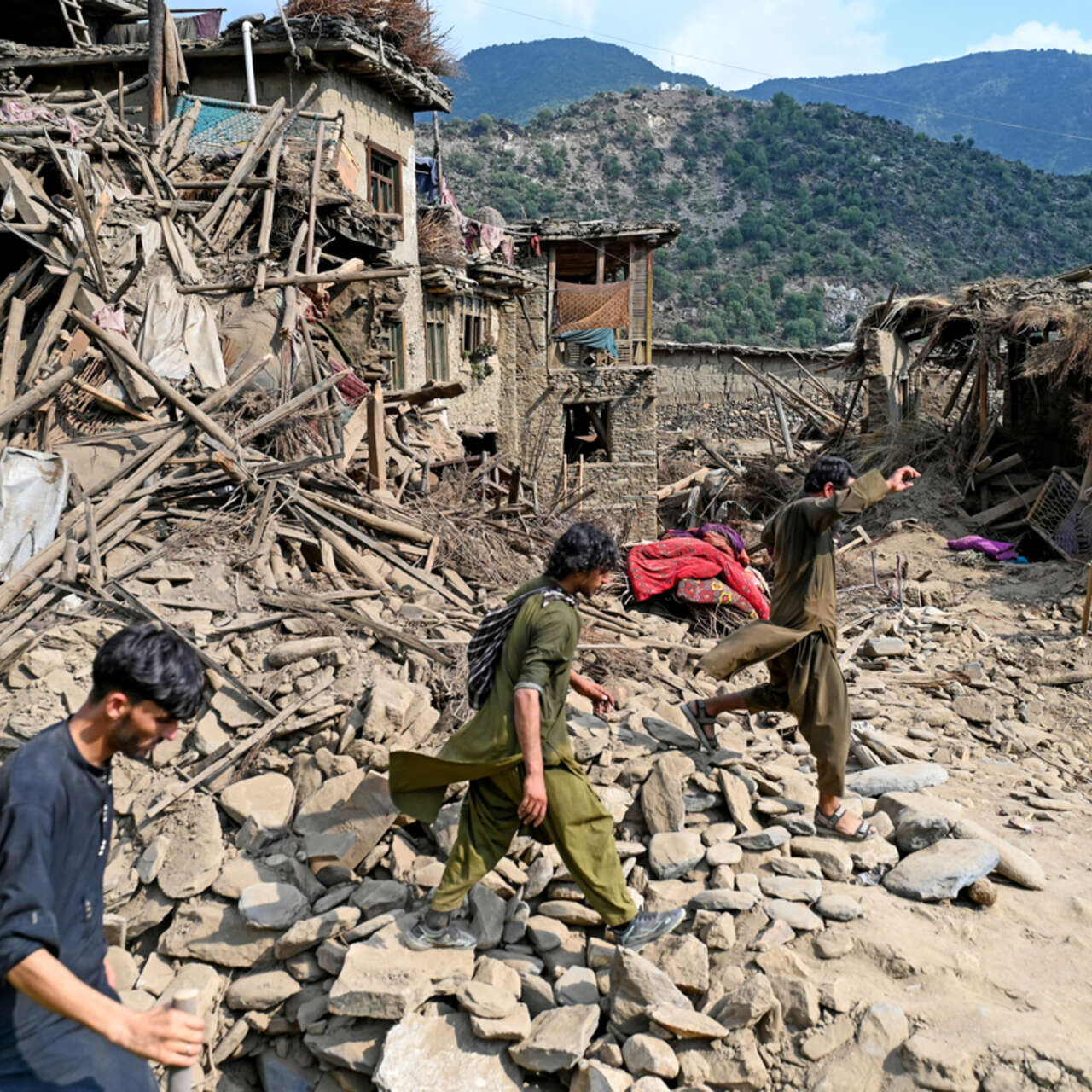 fghans walk past damaged houses, after earthquakes at Mazar Dara village in Nurgal district, Kunar province.