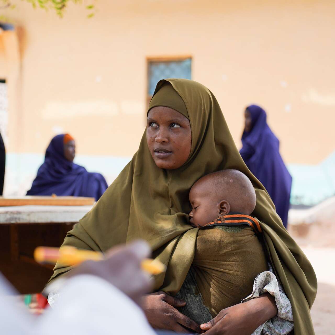 Eine Mutter hält ihr schlafendes Kind in den Armen, während sie eine IRC-Gesundheitsklinik in Somalia besucht.