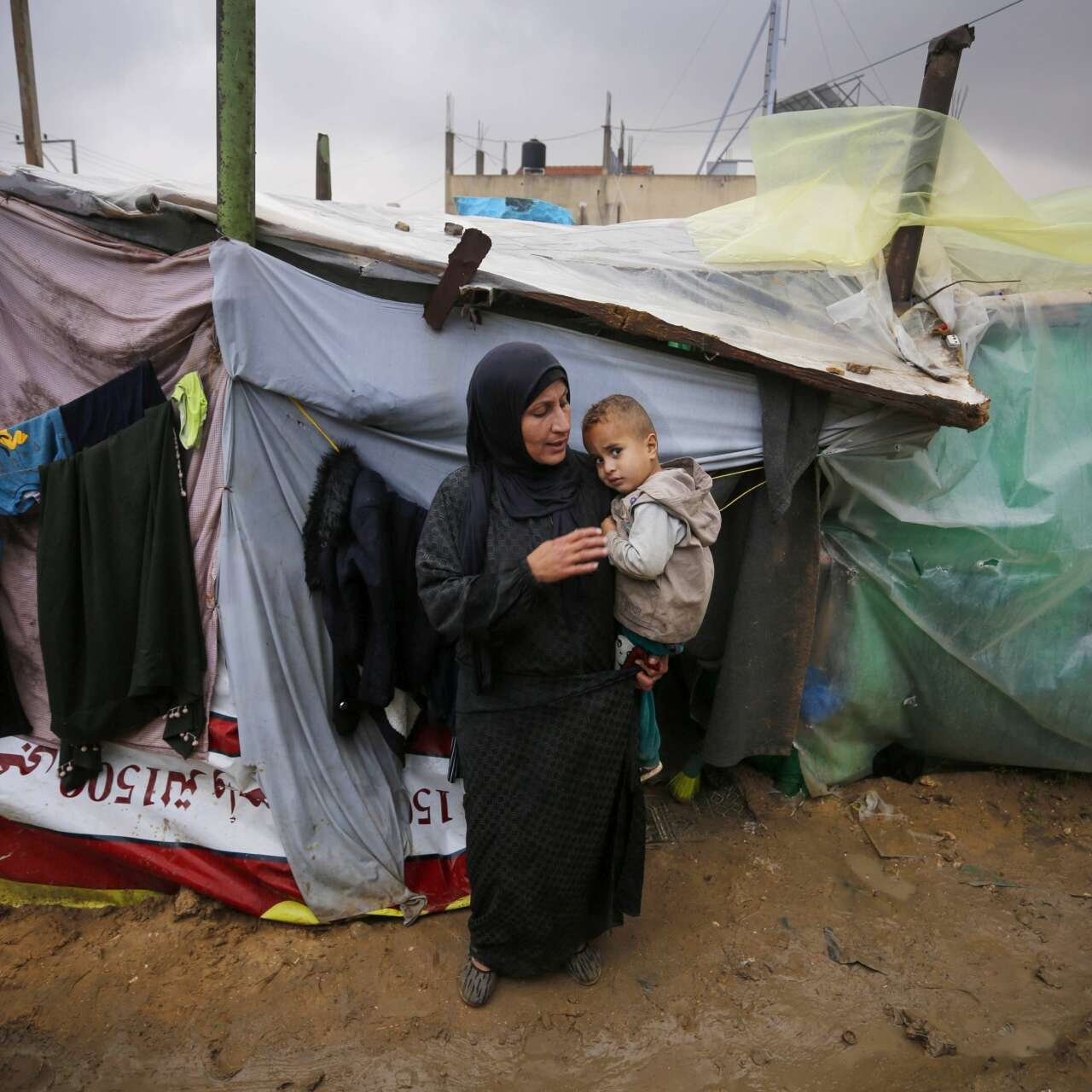 A mother holds her son in her arms outside their shelter in Gaza.