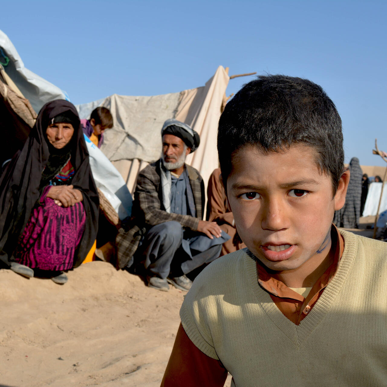 Two children sit inside their temporary shelter.