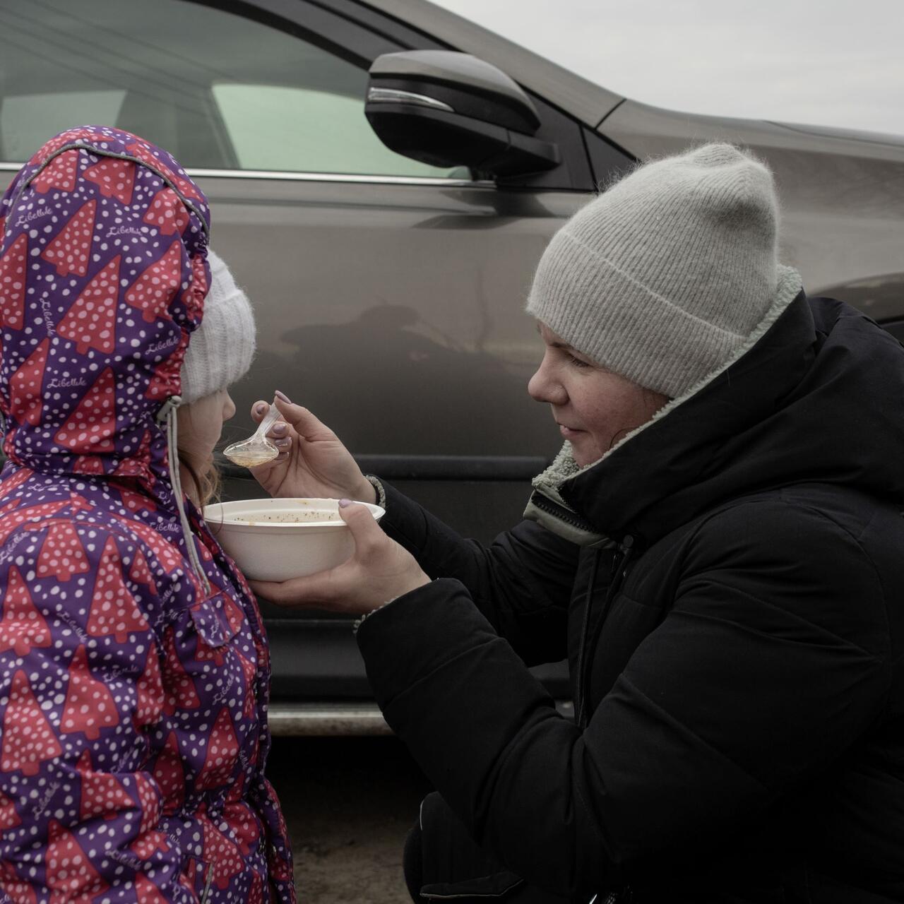 A woman spooning food into a child's mouth