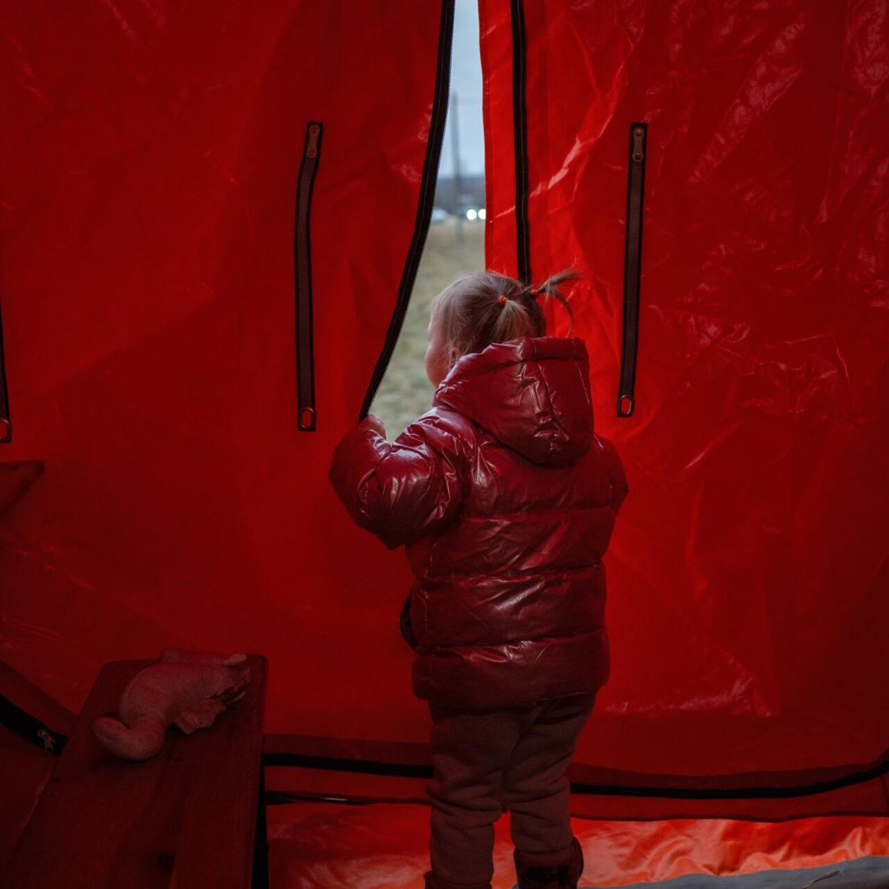 Iryna firstborn looking out of a tent in Poland 