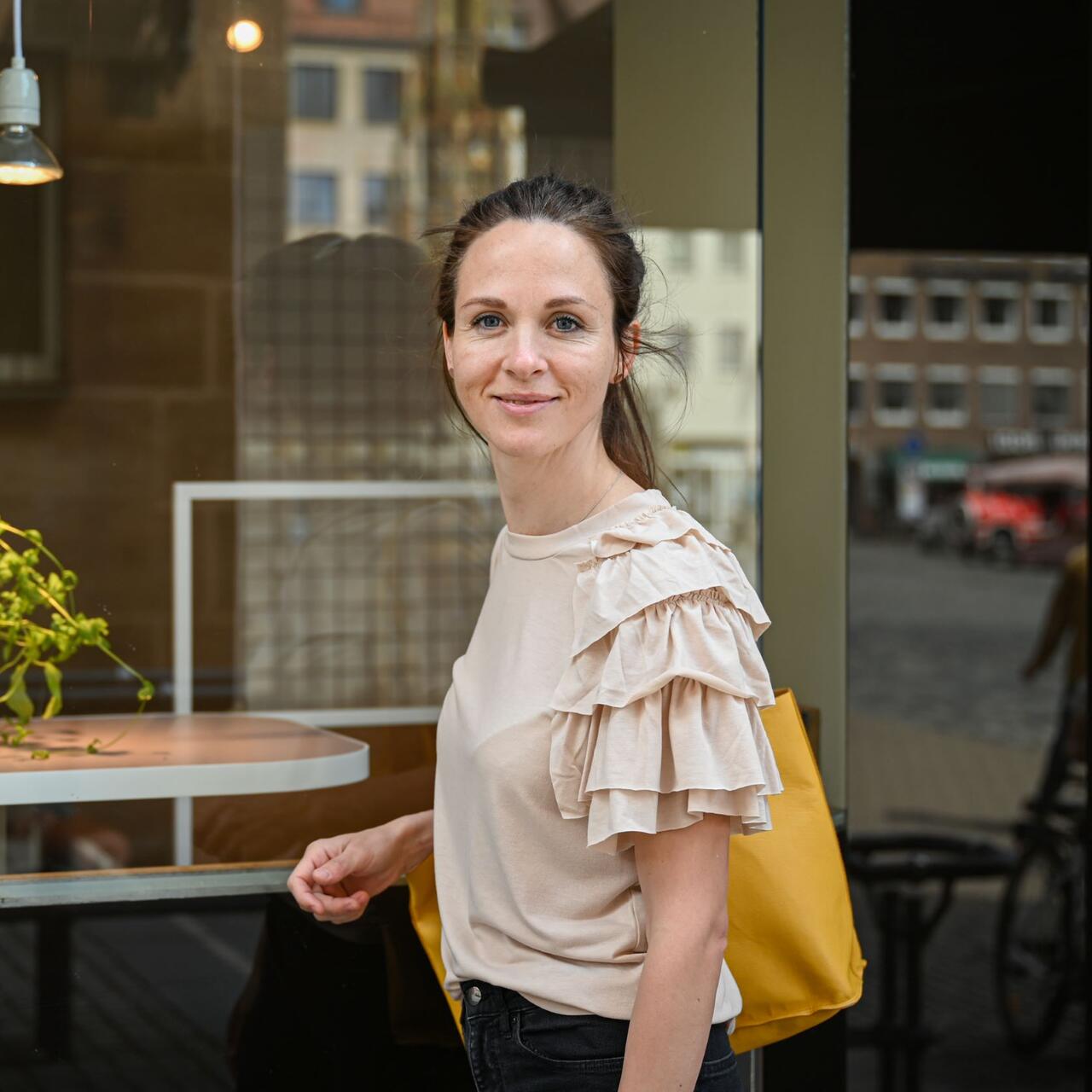 A woman standing in front of a shop window.