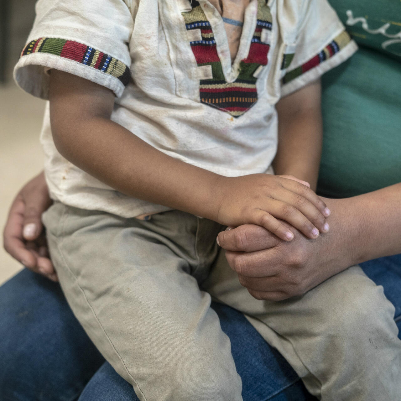 A Central American child sits on his mother's lap
