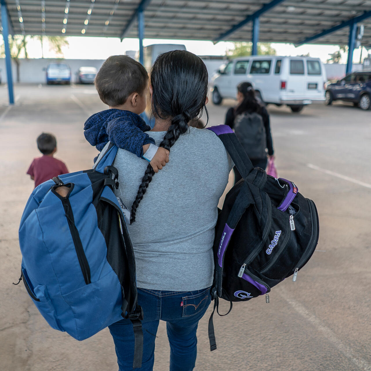 A Central American mother holds her child and two backpacks after arriving in Phoenix, Arizona