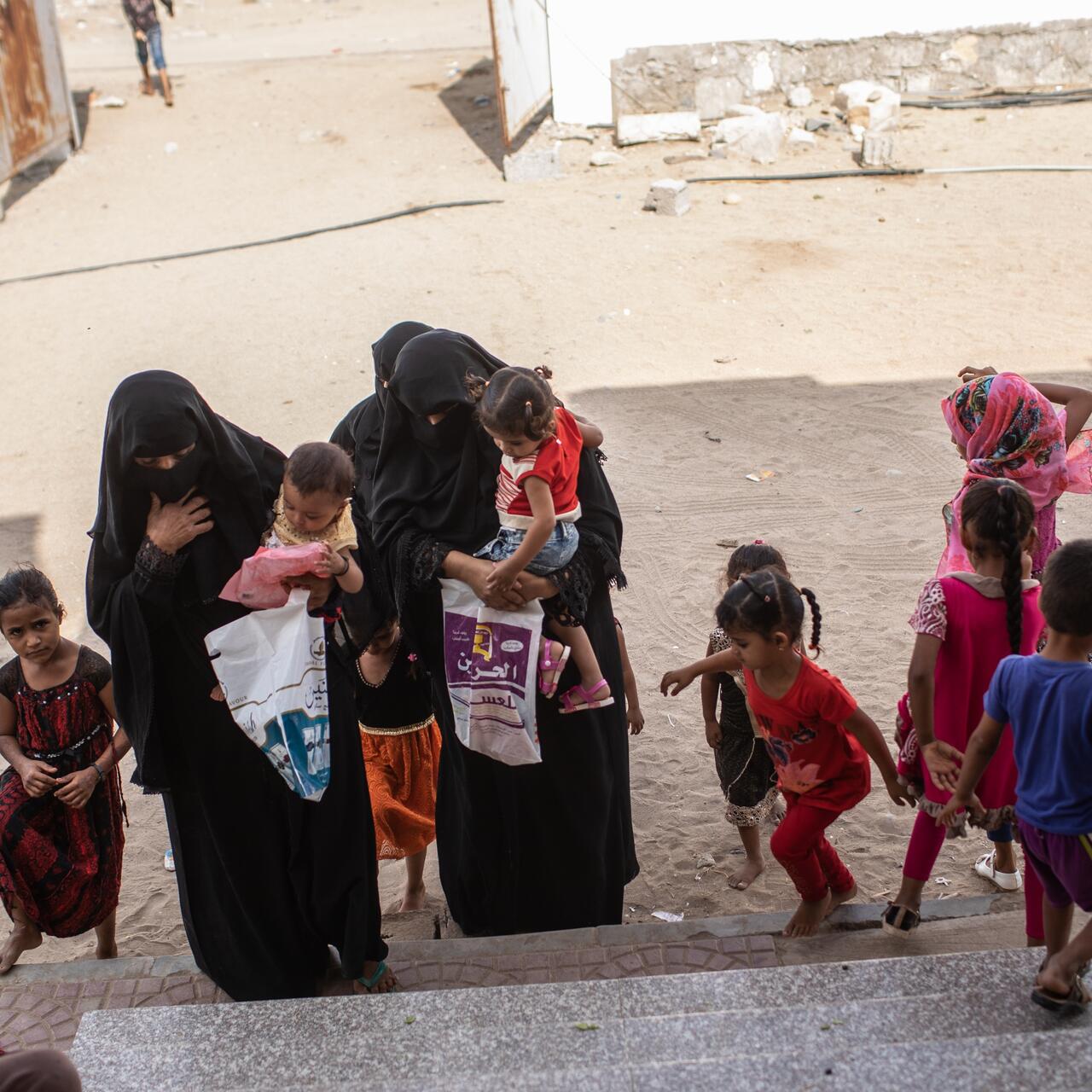 A group of mothers and children arrive at the steps of an International Rescue Committee center near Aden, Yemen