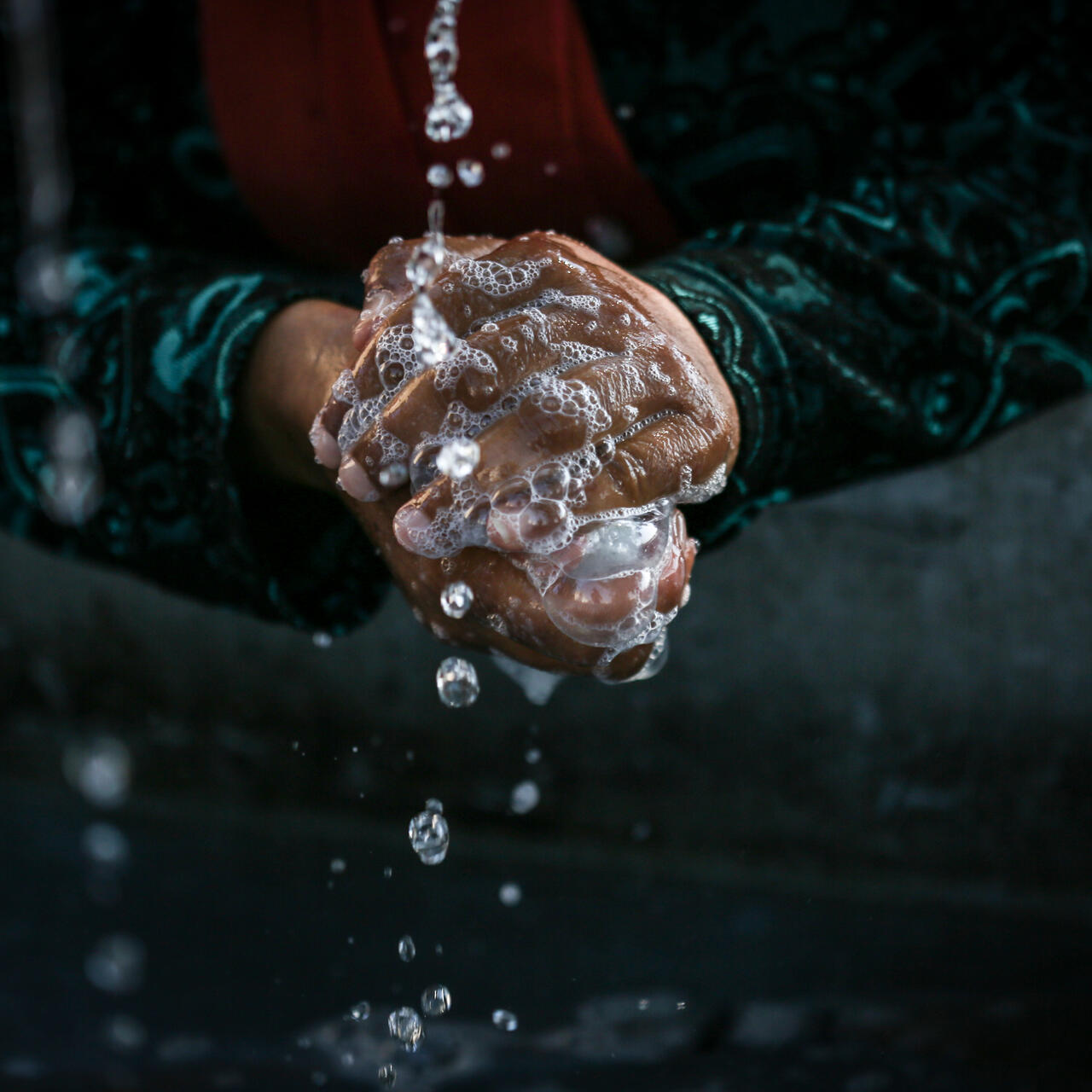 A woman cleans her hands at the Alexandria refugee camp in northern Greece, July 14, 2016.