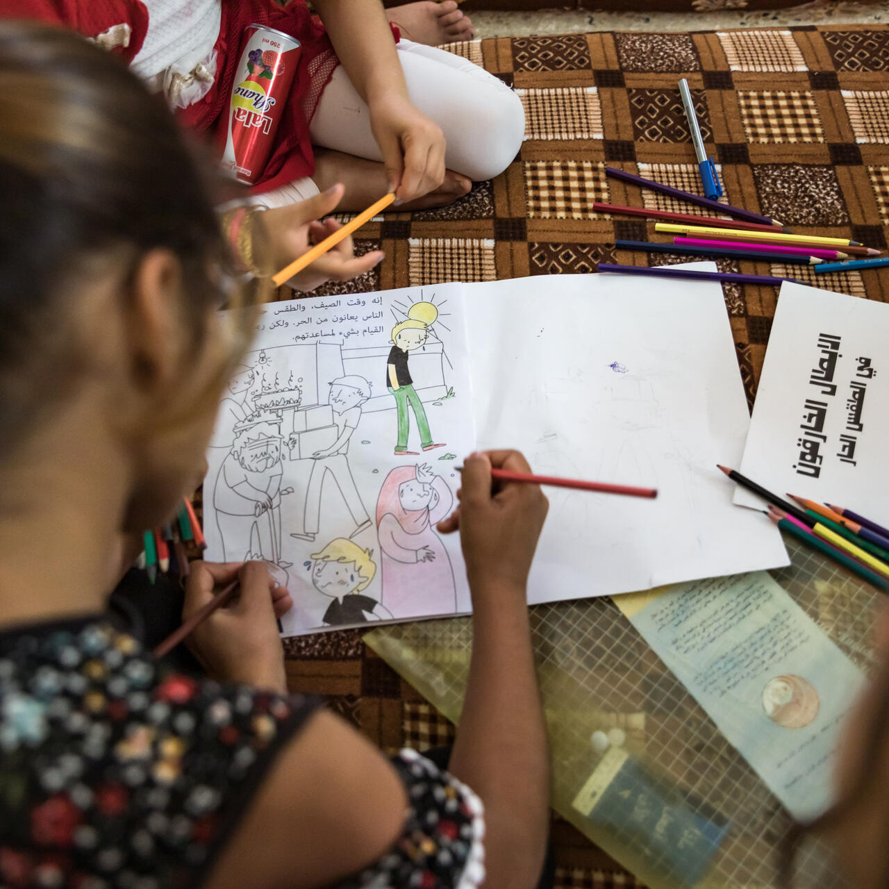 Children in Sinjar, Iraq sit on the floor of their home, coloring