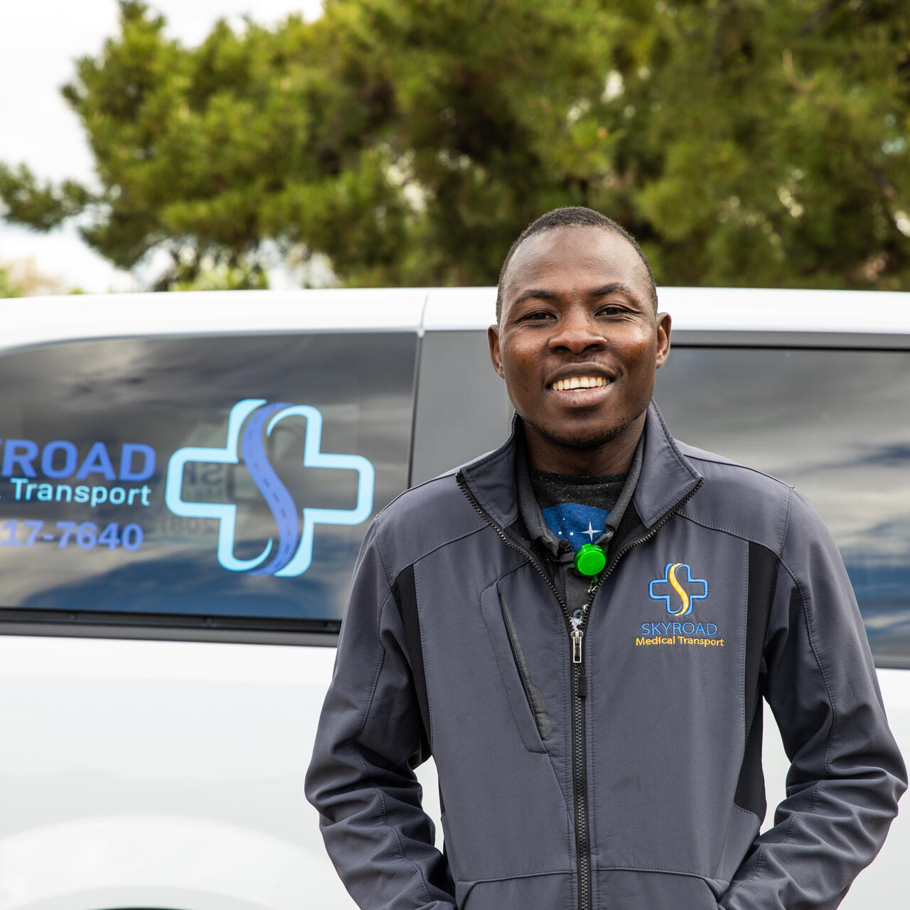 Jonathan Amissa stands in front of a van this is part of his company's fleet of medical transport vehicles.