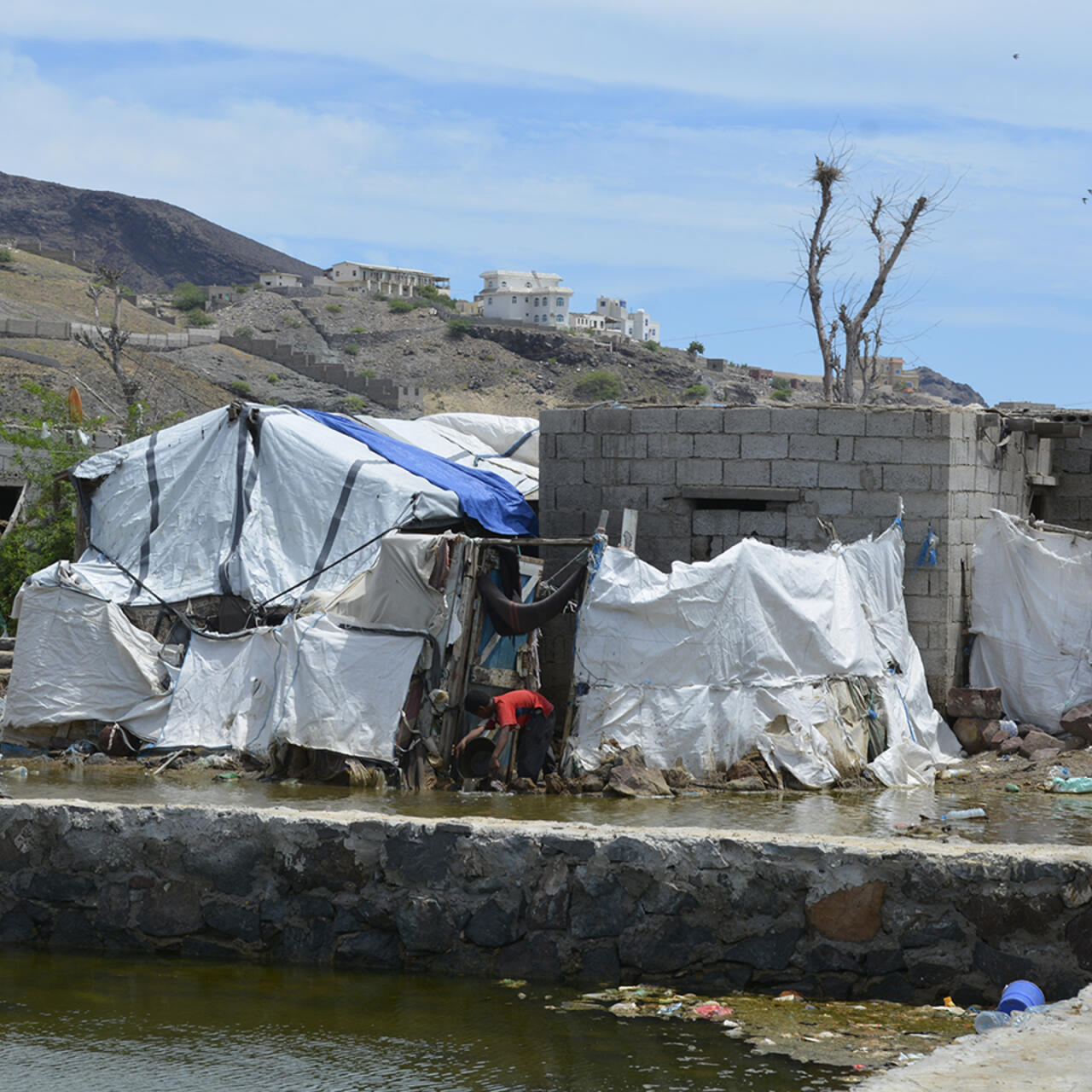 A displaced child bails water from a flooded tent near Aden, Yemen
